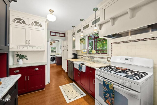 346 Stedman Pl, Monrovia, CA 91016 - kitchen with white range with gas stovetop, washer / clothes dryer, stainless steel dishwasher, wood finished floors, and custom exhaust hood