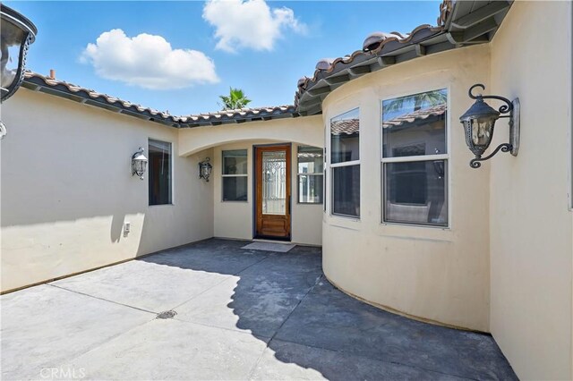 13045 Ridgewood Way, Chowchilla, CA 93610 - doorway to property featuring stucco siding, a patio, and a tiled roof