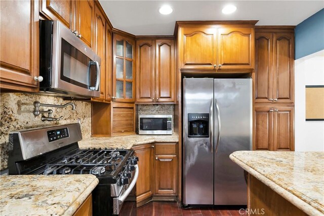 1914 S W View St, Los Angeles, CA 90016 - kitchen with appliances with stainless steel finishes, brown cabinets, light stone counters, glass insert cabinets, and recessed lighting