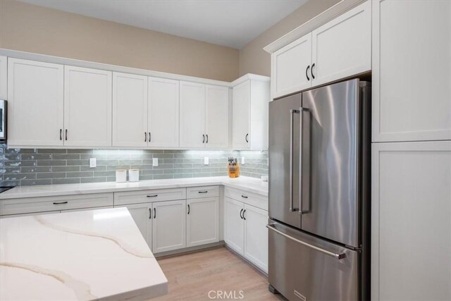 176 Tango Way, San Luis Obispo, CA 93401 - kitchen featuring appliances with stainless steel finishes, white cabinets, light stone counters, decorative backsplash, and light wood-type flooring