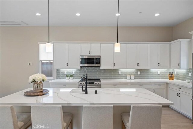 176 Tango Way, San Luis Obispo, CA 93401 - kitchen featuring appliances with stainless steel finishes, backsplash, white cabinets, a center island with sink, and a breakfast bar area