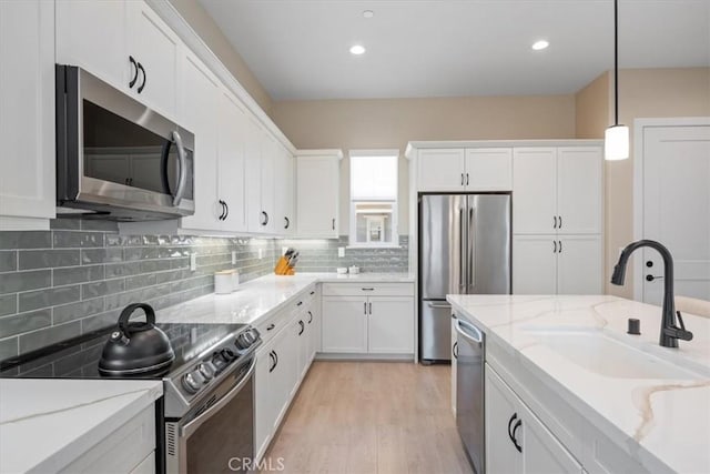 176 Tango Way, San Luis Obispo, CA 93401 - kitchen with stainless steel appliances, white cabinetry, decorative light fixtures, decorative backsplash, and light wood-style floors