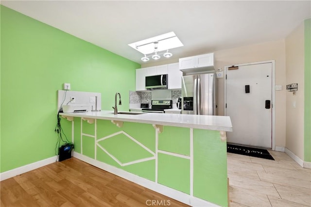3505 Angelucci St Unit 2E, San Diego, CA 92111 - kitchen featuring appliances with stainless steel finishes, a sink, a skylight, a peninsula, and a breakfast bar area