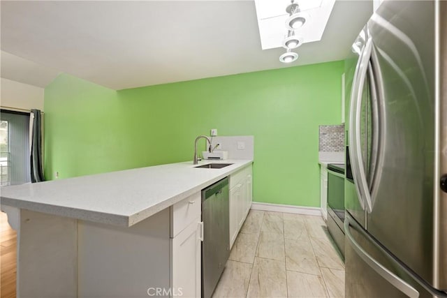 3505 Angelucci St Unit 2E, San Diego, CA 92111 - kitchen with appliances with stainless steel finishes, a skylight, a peninsula, a sink, and light countertops