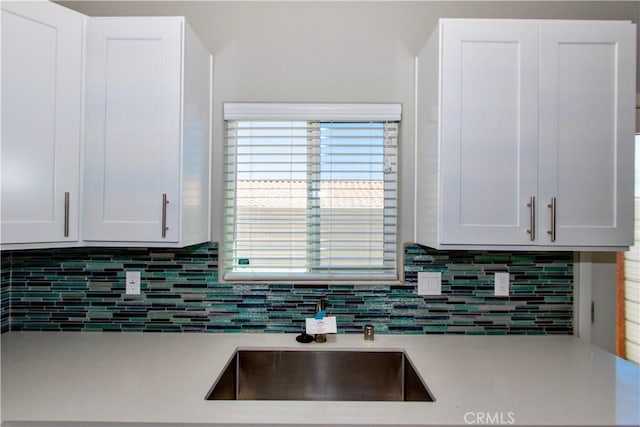 12612 Maui Way, Desert Hot Springs, CA 92240 - kitchen featuring light countertops, backsplash, white cabinetry, and a sink