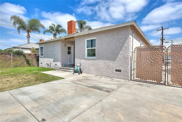 11206 Quinn St, Downey, CA 90241 - back of property with a gate, a chimney, stucco siding, a patio, and crawl space