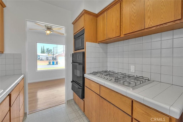 11206 Quinn St, Downey, CA 90241 - kitchen featuring black appliances, a ceiling fan, light flooring, a warming drawer, and decorative backsplash
