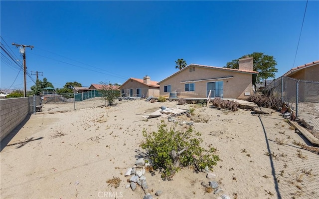 66427 3rd St, Desert Hot Springs, CA 92240 - back of house with a fenced backyard, a chimney, and stucco siding