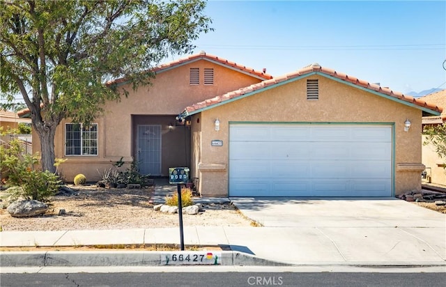 66427 3rd St, Desert Hot Springs, CA 92240 - mediterranean / spanish house with concrete driveway, a garage, stucco siding, and a tile roof