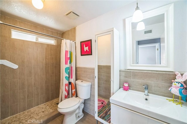6114 Sard St, Rancho Cucamonga, CA 91701 - bathroom featuring toilet, a tile shower, tile walls, and vanity