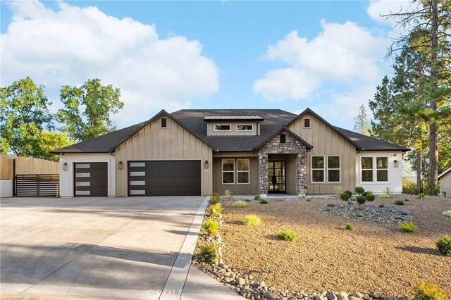 4956 Malibu Dr, Paradise, CA 95969 - view of front of house featuring a garage, driveway, a shingled roof, board and batten siding, and stone siding