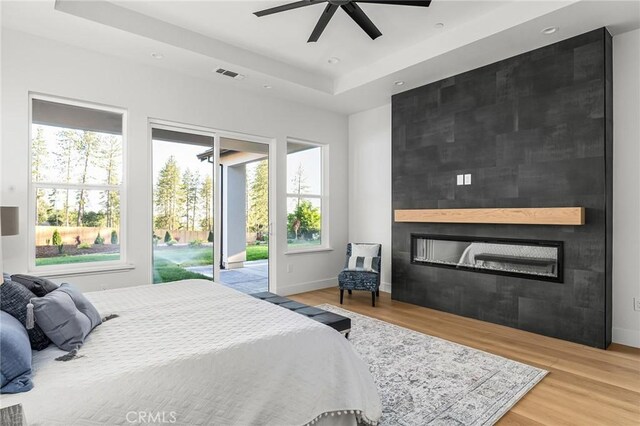 4956 Malibu Dr, Paradise, CA 95969 - bedroom with access to exterior, wood finished floors, a large fireplace, a raised ceiling, and baseboards
