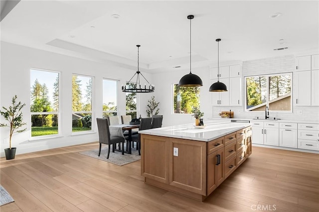 4956 Malibu Dr, Paradise, CA 95969 - kitchen featuring a tray ceiling, a sink, white cabinets, a chandelier, and light wood-type flooring