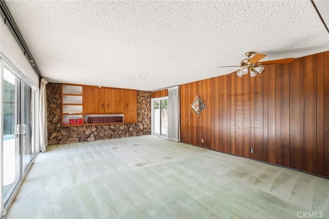8754 Prichard St, Downey, CA 90242 - unfurnished living room featuring light colored carpet, a textured ceiling, ceiling fan, and wooden walls