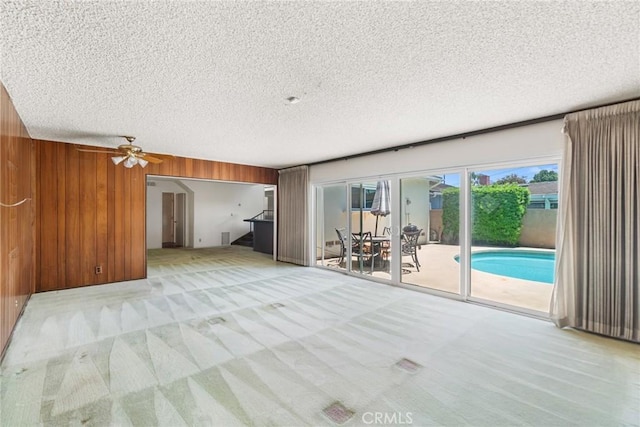 8754 Prichard St, Downey, CA 90242 - unfurnished living room featuring light carpet, stairway, wooden walls, a textured ceiling, and ceiling fan