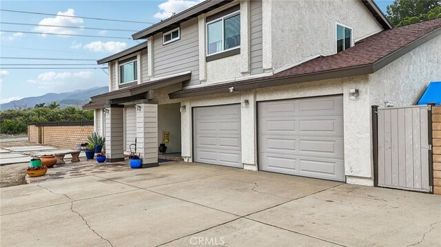 7906 Appaloosa Ct, Rancho Cucamonga, CA 91701 - back of house featuring stucco siding, driveway, an attached garage, and a mountain view