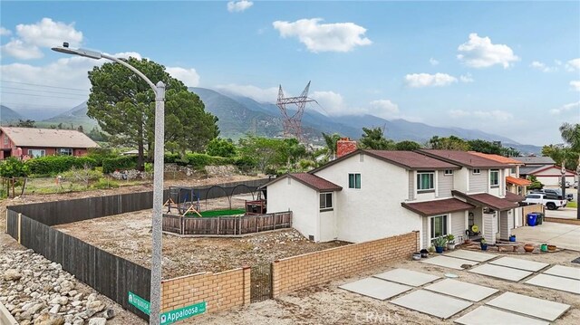 7906 Appaloosa Ct, Rancho Cucamonga, CA 91701 - view of side of home featuring a mountain view, a fenced backyard, a patio, stucco siding, and a chimney
