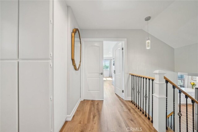 7906 Appaloosa Ct, Rancho Cucamonga, CA 91701 - hall featuring an upstairs landing, light wood-type flooring, healthy amount of natural light, vaulted ceiling, and baseboards