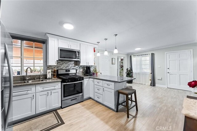 20402 Pioneer Blvd, Lakewood, CA 90715 - kitchen with appliances with stainless steel finishes, a peninsula, light wood-style flooring, white cabinets, and a kitchen bar