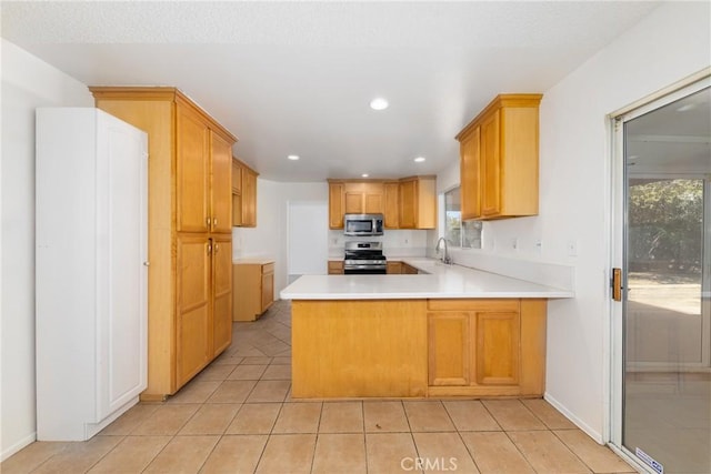 4231 Sage Ct, Palmdale, CA 93552 - kitchen featuring appliances with stainless steel finishes, a sink, a peninsula, light tile patterned flooring, and light countertops