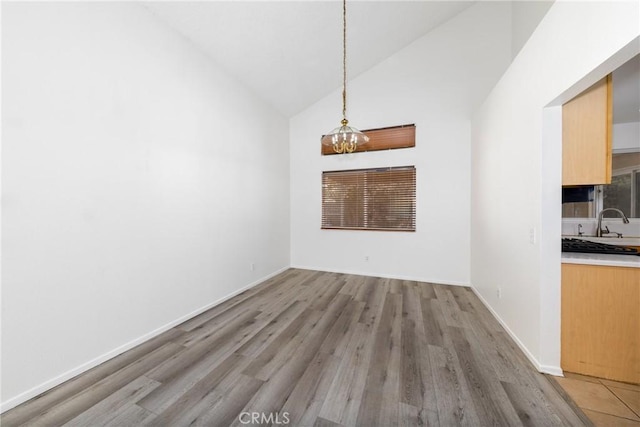 4231 Sage Ct, Palmdale, CA 93552 - unfurnished dining area with a chandelier, high vaulted ceiling, light wood-style flooring, and baseboards