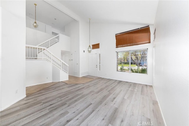 4231 Sage Ct, Palmdale, CA 93552 - unfurnished living room featuring high vaulted ceiling, wood finished floors, stairway, and baseboards