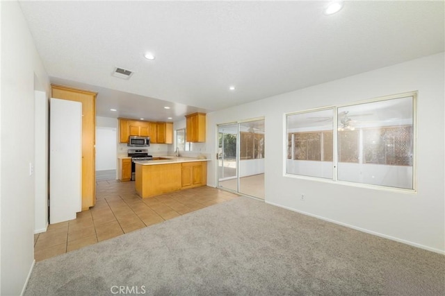 4231 Sage Ct, Palmdale, CA 93552 - kitchen featuring appliances with stainless steel finishes, light colored carpet, recessed lighting, open floor plan, and light countertops
