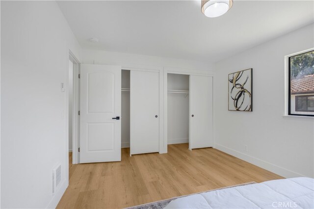 676 N 12th St Unit 21, Grover Beach, CA 93433 - unfurnished bedroom featuring two closets, light wood-style floors, and baseboards
