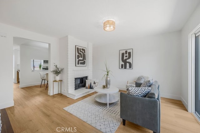 676 N 12th St Unit 21, Grover Beach, CA 93433 - living room featuring light wood-style floors, a brick fireplace, and baseboards