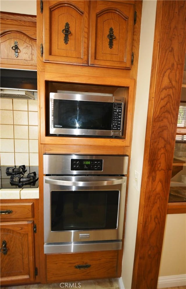 11514 Beverly Blvd, Whittier, CA 90601 - kitchen featuring stainless steel appliances, brown cabinetry, tasteful backsplash, light countertops, and baseboards