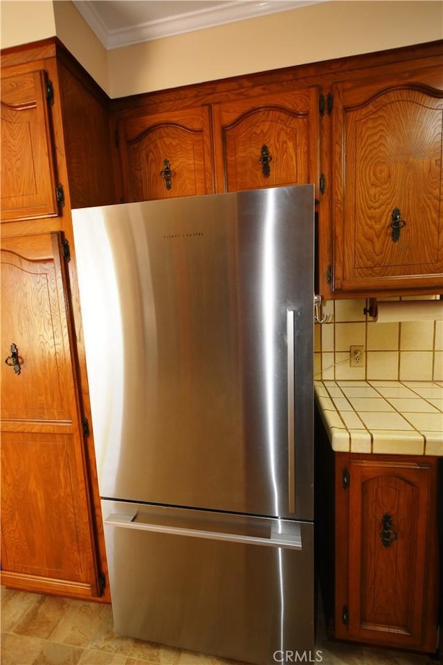 11514 Beverly Blvd, Whittier, CA 90601 - detailed view of freestanding refrigerator, ornamental molding, tile counters, and brown cabinets