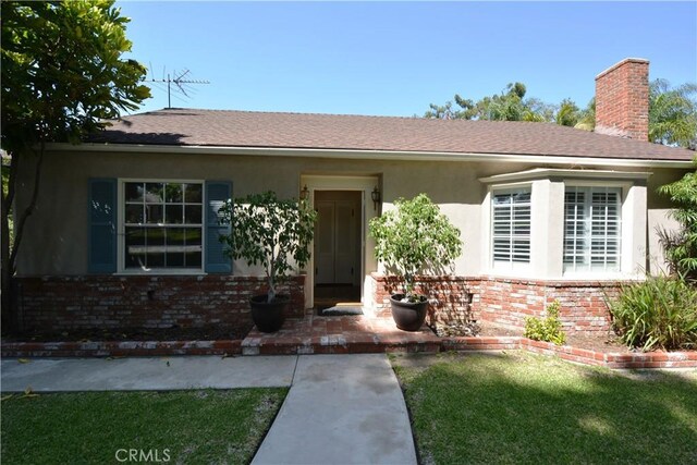 11514 Beverly Blvd, Whittier, CA 90601 - view of front of property featuring brick siding, a chimney, stucco siding, a front lawn, and roof with shingles