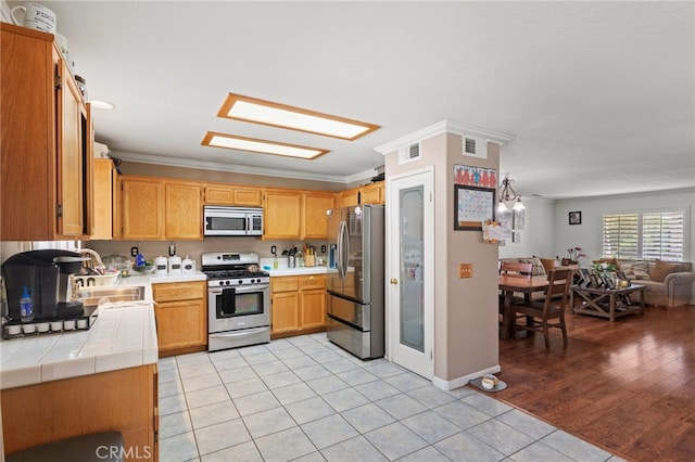 38701 Annette Ave, Palmdale, CA 93551 - kitchen featuring appliances with stainless steel finishes, a sink, light tile patterned floors, open floor plan, and tile counters