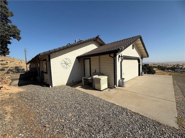 9307 Banderilla Dr, La Grange, CA 95329 - view of side of property with central AC unit, an attached garage, driveway, and a tiled roof