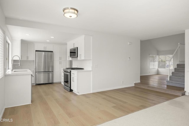196 Mariposa Dr, Camarillo, CA 93012 - kitchen featuring appliances with stainless steel finishes, a sink, light countertops, open floor plan, and light wood-style floors
