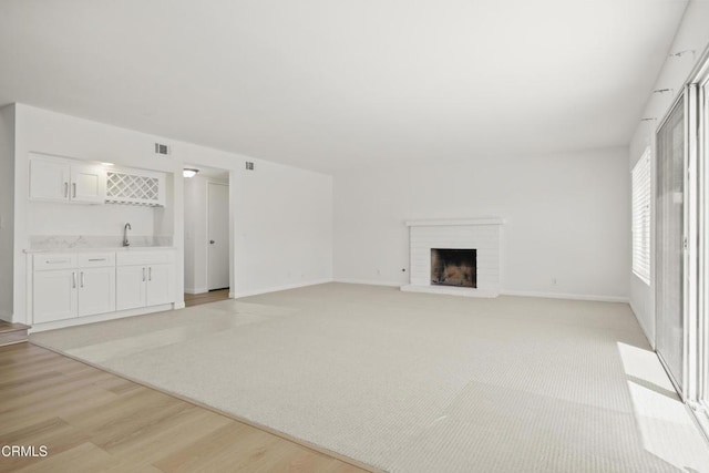 196 Mariposa Dr, Camarillo, CA 93012 - unfurnished living room featuring bar with sink, light wood-type flooring, a fireplace, and baseboards