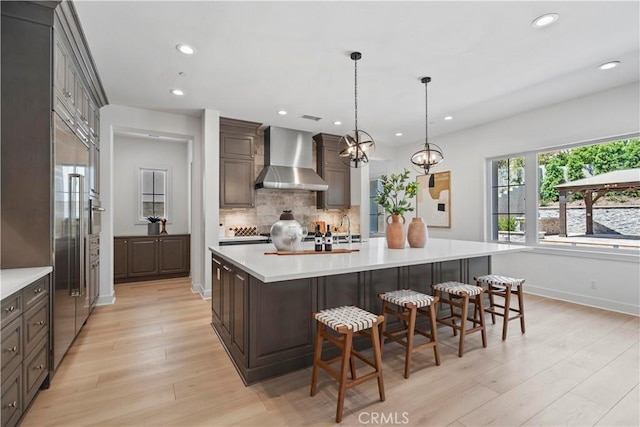51 Eider Run, Irvine, CA 92618 - kitchen with wall chimney exhaust hood, backsplash, light countertops, light wood-style flooring, and recessed lighting