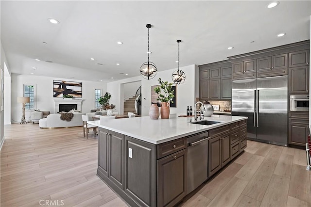 51 Eider Run, Irvine, CA 92618 - kitchen with stainless steel appliances, light countertops, recessed lighting, a fireplace, and light wood-style floors