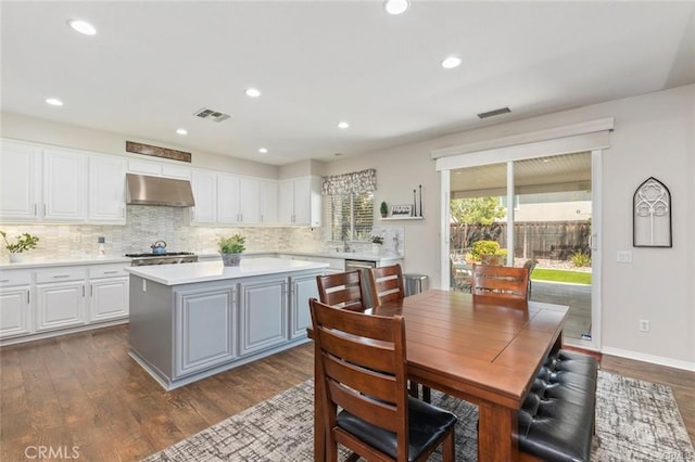 27840 Pointe Breeze Dr, Menifee, CA 92585 - kitchen featuring under cabinet range hood, white cabinetry, light countertops, a kitchen island, and backsplash