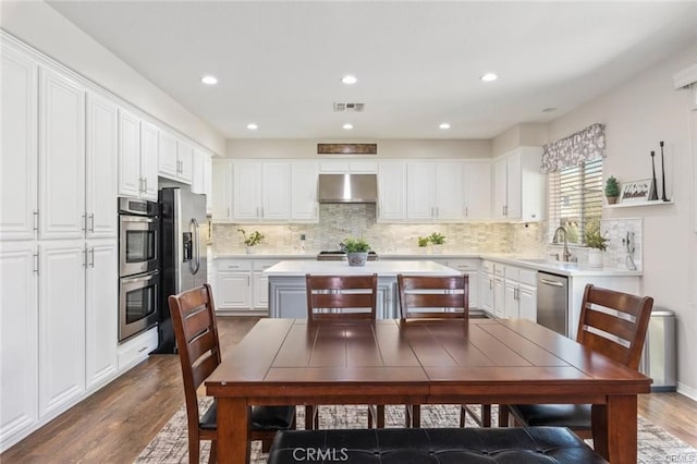 27840 Pointe Breeze Dr, Menifee, CA 92585 - kitchen featuring under cabinet range hood, appliances with stainless steel finishes, wood finished floors, white cabinets, and light countertops