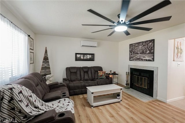 3833 Kennedy St, Le Grand, CA 95333 - living area with a wall unit AC, light wood-style flooring, a ceiling fan, a fireplace with flush hearth, and baseboards