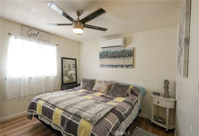 3833 Kennedy St, Le Grand, CA 95333 - bedroom with a wall unit AC, wood finished floors, baseboards, a textured ceiling, and ceiling fan