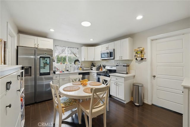 4819 Church St, Pico Rivera, CA 90660 - kitchen featuring stainless steel appliances, dark wood-style floors, white cabinets, decorative backsplash, and a sink