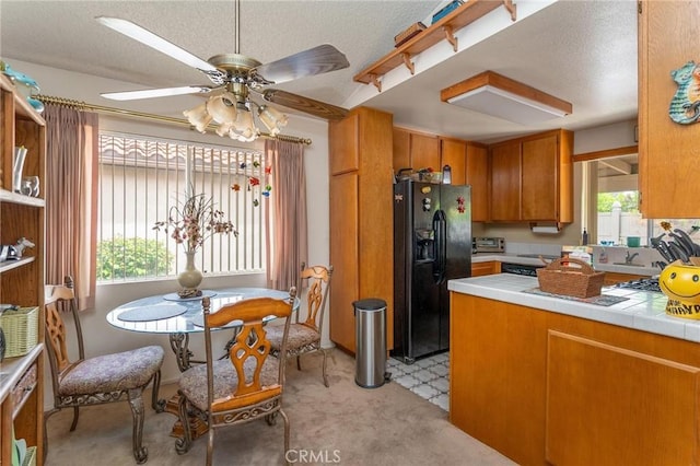 26181 Goldenwood St, Menifee, CA 92586 - kitchen featuring black refrigerator with ice dispenser, brown cabinetry, a ceiling fan, a textured ceiling, and light carpet