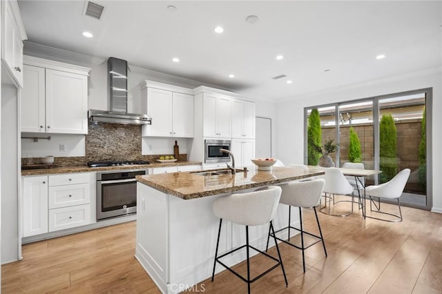 156 Barrow, Irvine, CA 92620 - kitchen with appliances with stainless steel finishes, wall chimney range hood, a sink, decorative backsplash, and an island with sink
