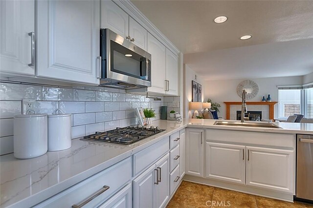24650 Via Melinda, Yorba Linda, CA 92887 - kitchen featuring stainless steel appliances, a fireplace, backsplash, white cabinets, and a sink
