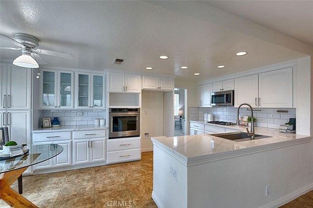 24650 Via Melinda, Yorba Linda, CA 92887 - kitchen featuring stainless steel appliances, a sink, tasteful backsplash, light countertops, and glass insert cabinets
