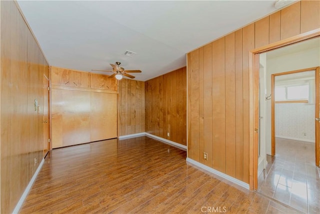 7236 Hellman Ave, Rancho Cucamonga, CA 91701 - empty room featuring a ceiling fan, wooden walls, light wood-style floors, and baseboards