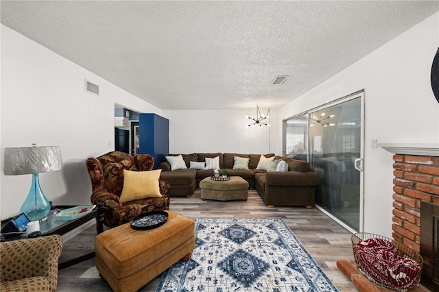 5015 Berryhill Pl, Riverside, CA 92507 - living area featuring wood finished floors, a chandelier, a textured ceiling, and a fireplace