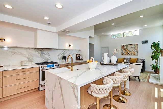 9539 Gladbeck Ave, Northridge, CA 91324 - kitchen with gas stove, light brown cabinets, light wood finished floors, backsplash, and a kitchen bar
